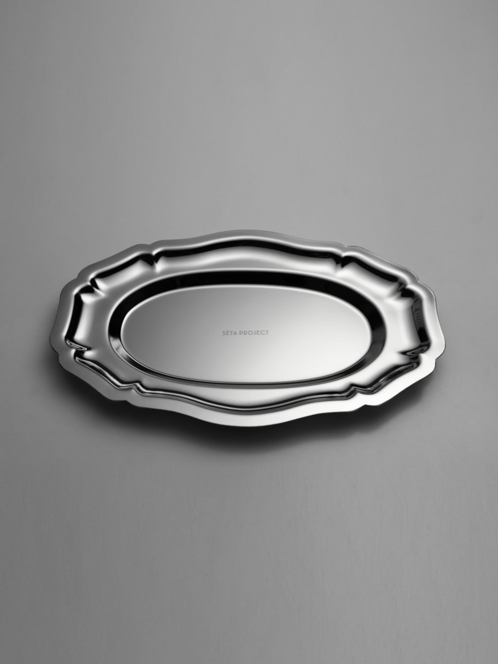 Oval stainless steel tray with decorative scalloped edges and polished finish.