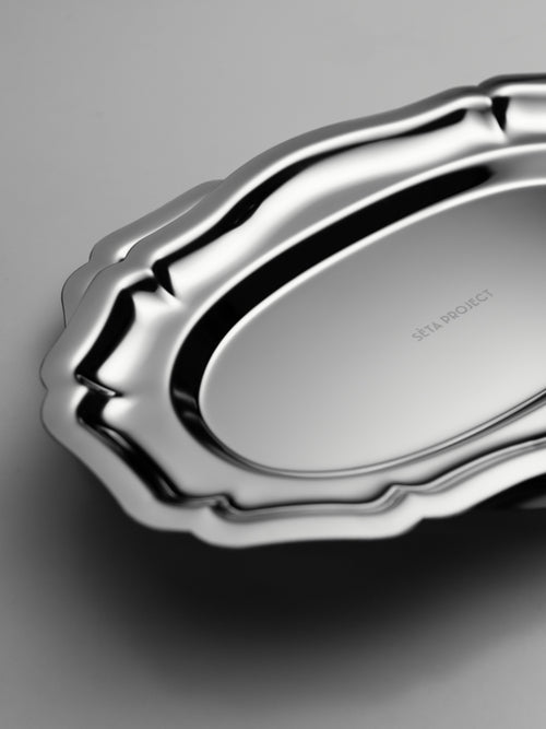 Oval stainless steel tray with scalloped edges and polished finish.