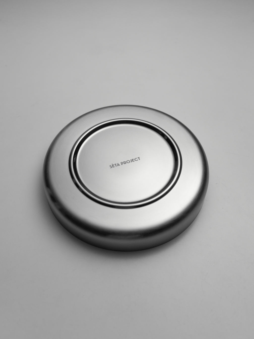 Oval stainless steel SOLIS plate with smooth polished finish, shown upside down.