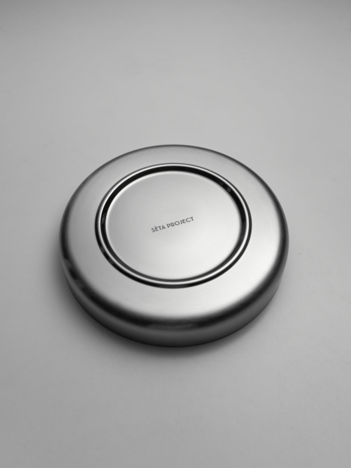 Oval stainless steel SOLIS plate with smooth polished finish, shown upside down.